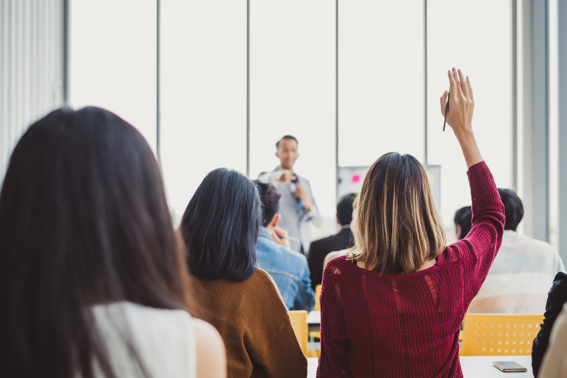 Womaning raising her hand to ask a question in a group