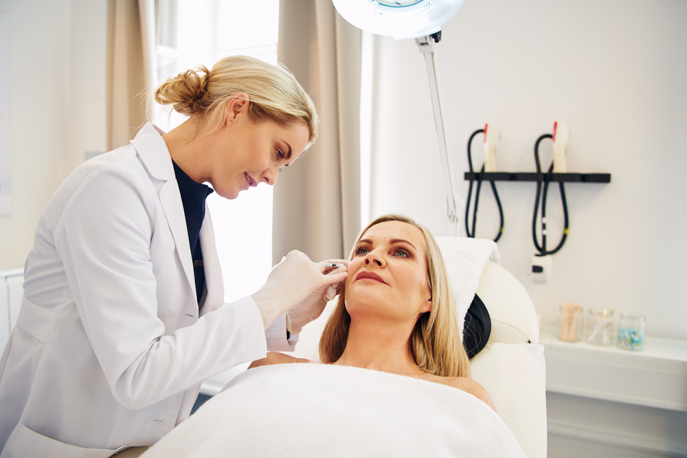 Smiling female doctor administers Botox injection to mature woman