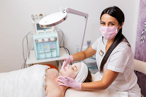 Employee from a medical spa applying a facial mask on a customer