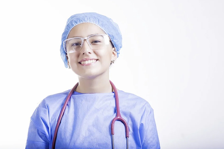 A smiling aesthetic nurse wearing a blue cap 