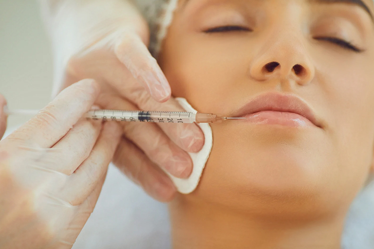An aesthetic nurse injecting lip filler to a patient