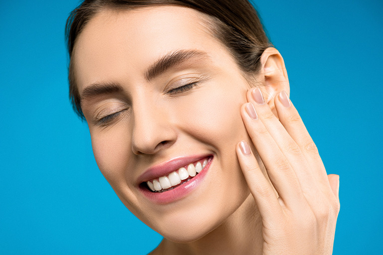 A woman smiling and lightly touching her face after a successful Botox injection
