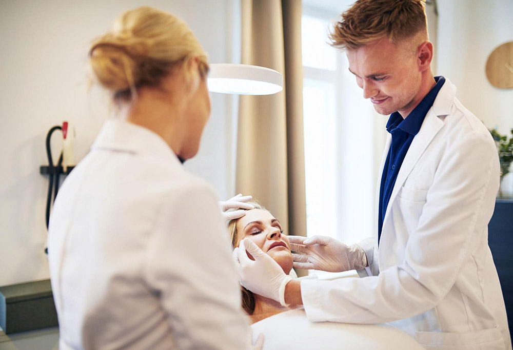 Two skincare specialists assessing the skin of a patient