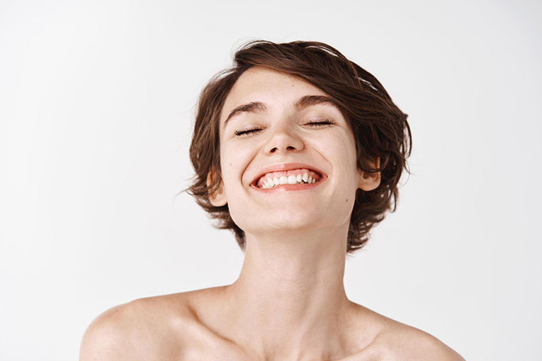 A smiling woman with short hair and glowing skin indicating a healthy skin microbiome