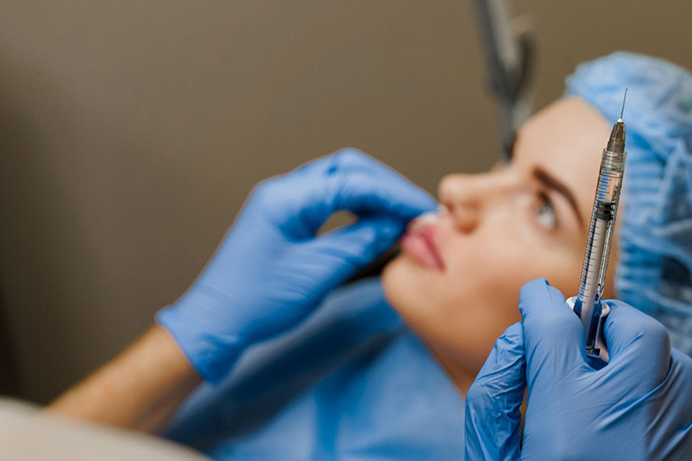 An aesthetician gets a patient ready for a dermal filler injection 