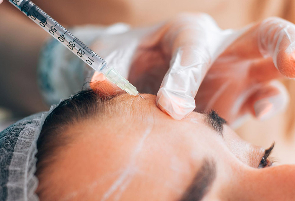 A young woman gets a preventative Botox injection on her forehead