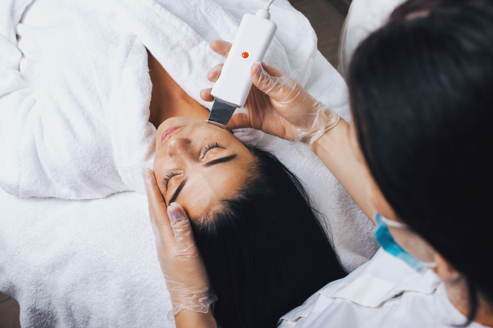 An aesthetician uses an ultrasound cosmetology scrubber on a patient
