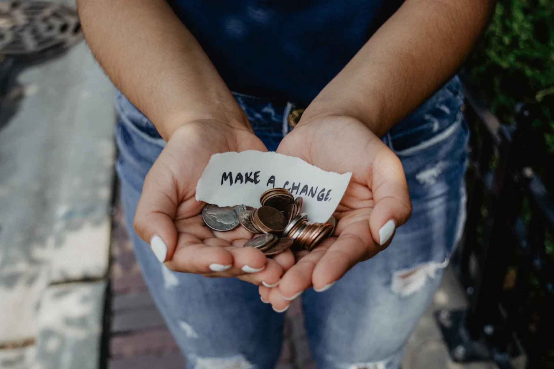 A person holding coins and a paper that says “make a change”