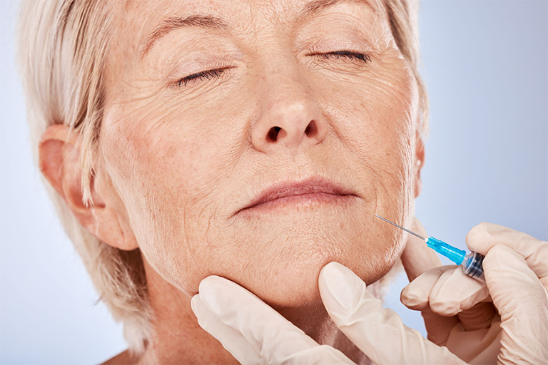  An older woman being injected with dermal filler near her mouth