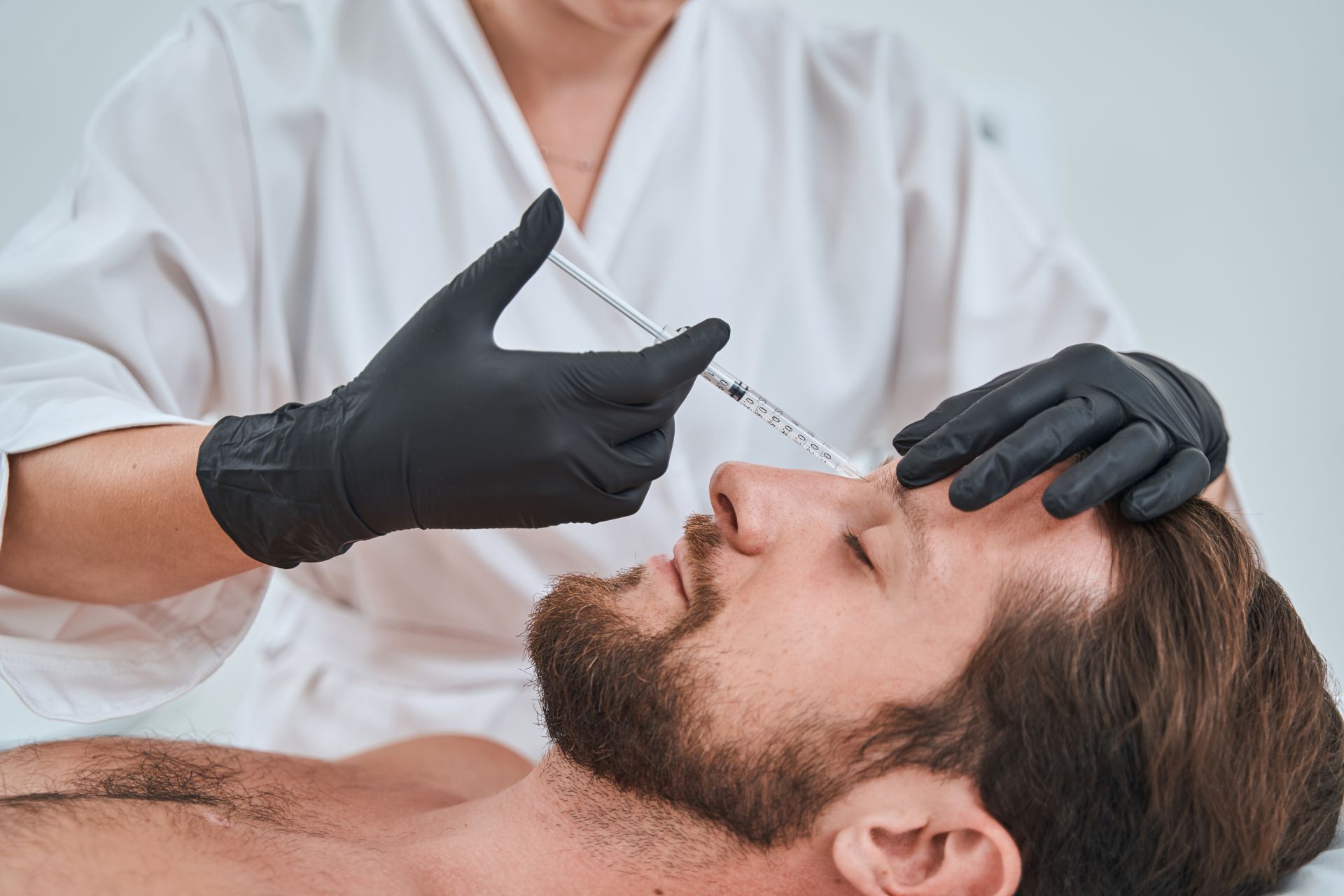 A man getting injected with dermal filler between his eyebrows
