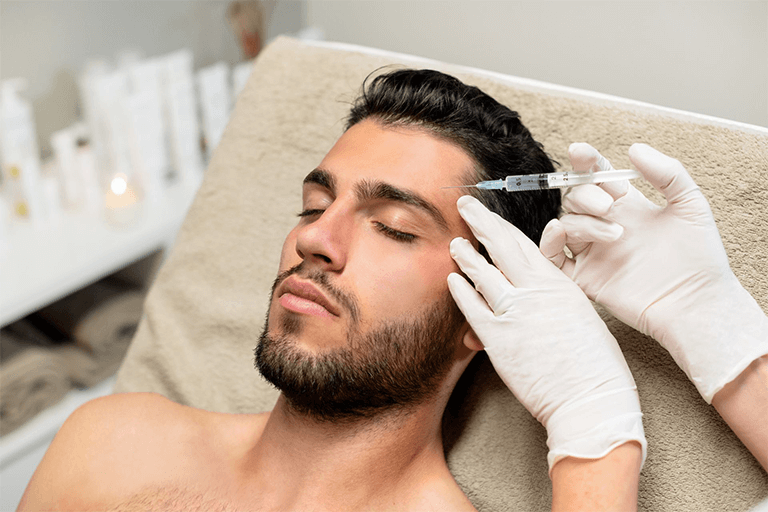 An aesthetic practitioner injecting filler into a man’s forehead 