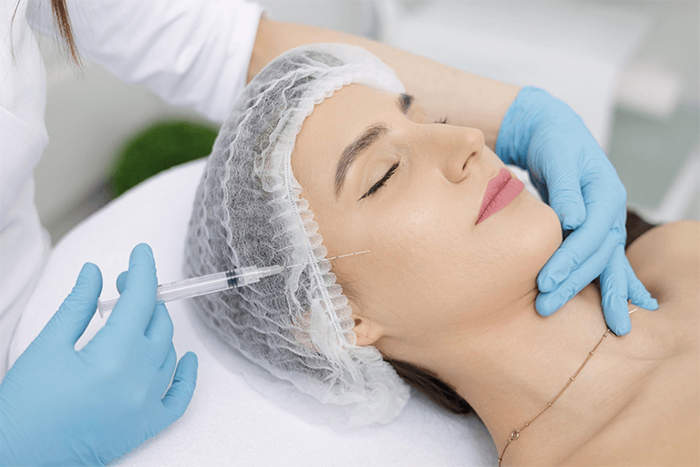 A relaxed woman receiving a filler injection on her cheek 