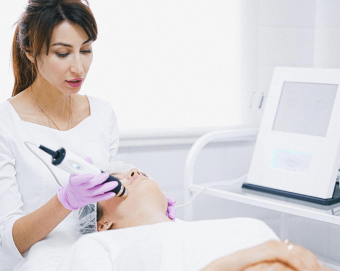 A clinician performing a treatment on a woman’s face