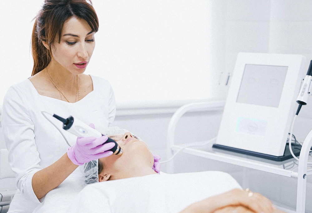 A clinician performing a treatment on a woman’s face