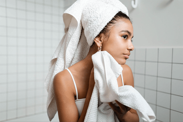 Woman fresh from the shower, drying her face with a towel 